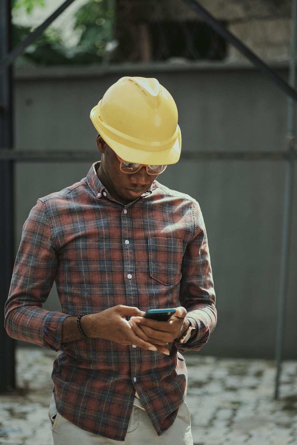 An electrician in a hard hat and a checked shirt reading his phone