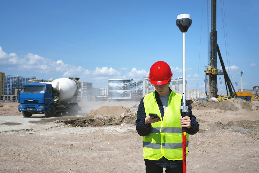 A worker in a hard hat on site, reading a phone