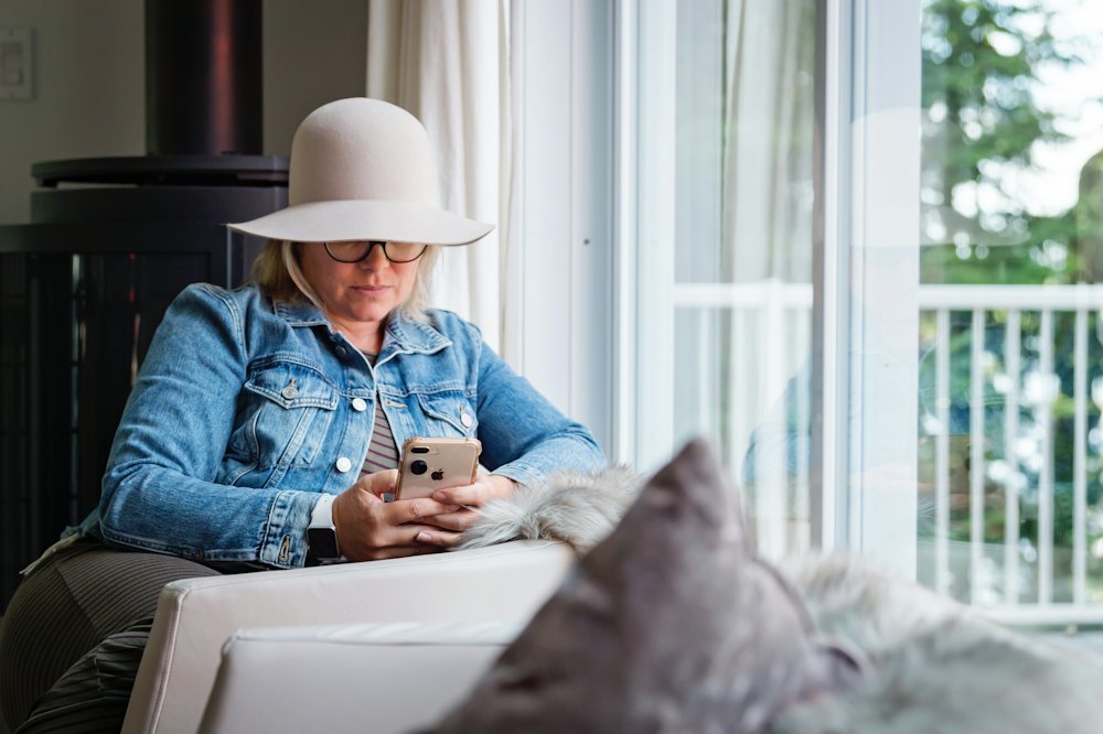 A woman at home on her sofa reading her phone