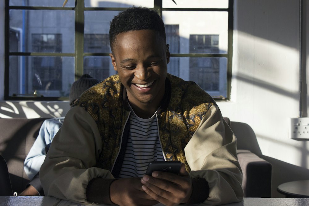 A man at home smiling at his phone