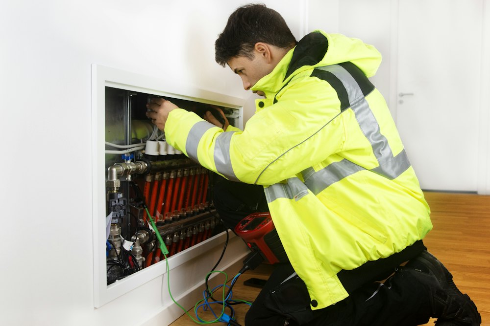 An installer in a high visibility jacket working at a heating manifold
